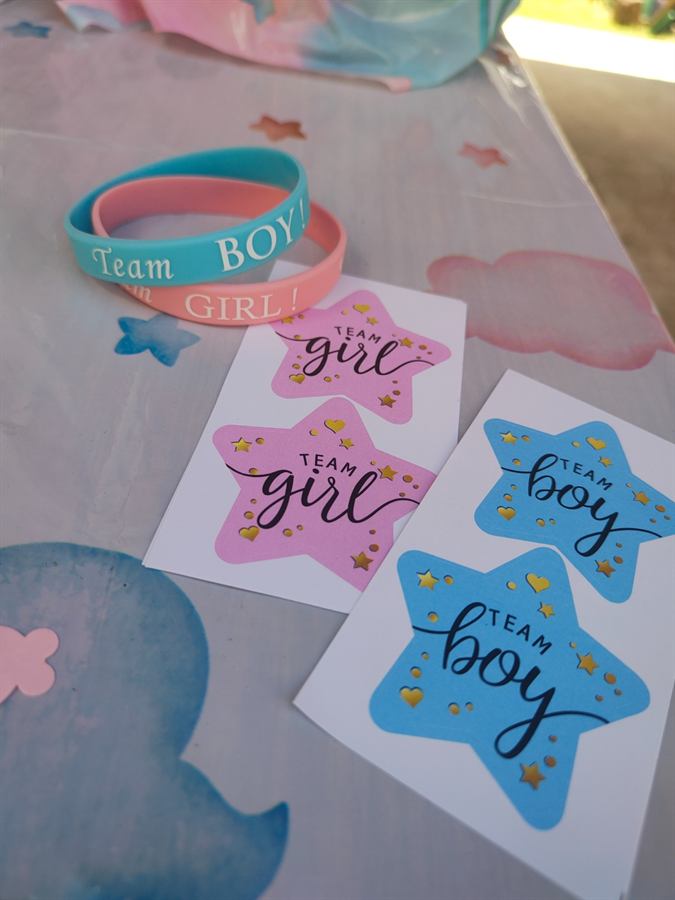Cartoncini a forma di stella con le scritte Team girl e Team boy, accanto ai braccialetti