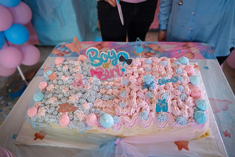 Torta rettangolare decorata con ciuffi di panna rosa e azzurri, meringhe e topper con la scritta Boy or Girl